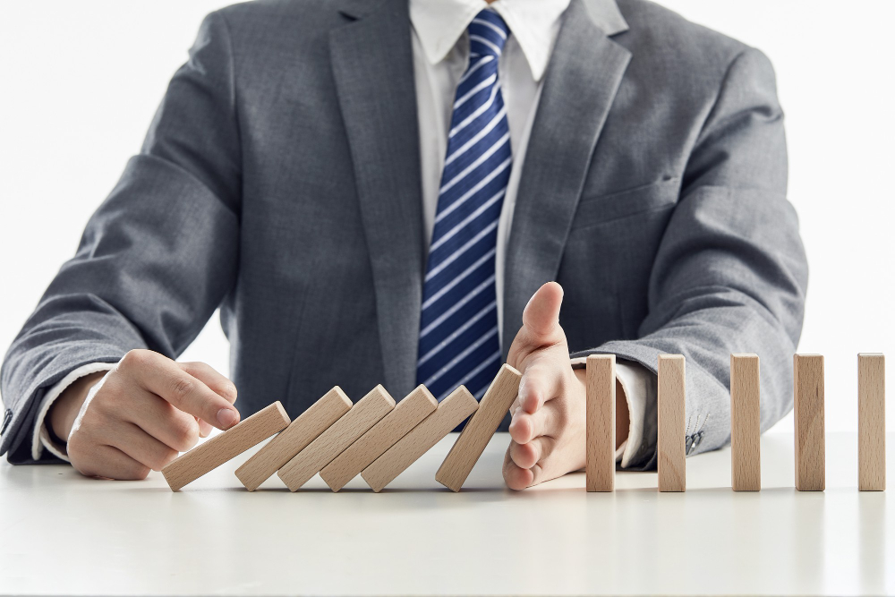 Businessman suit protecting wooden blocks from falling domino effect